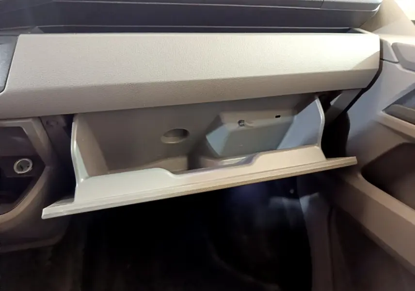 Vue intérieure du vide-poche ouvert côté passager du Volkswagen Transporter blanc, montrant son rangement spacieux.