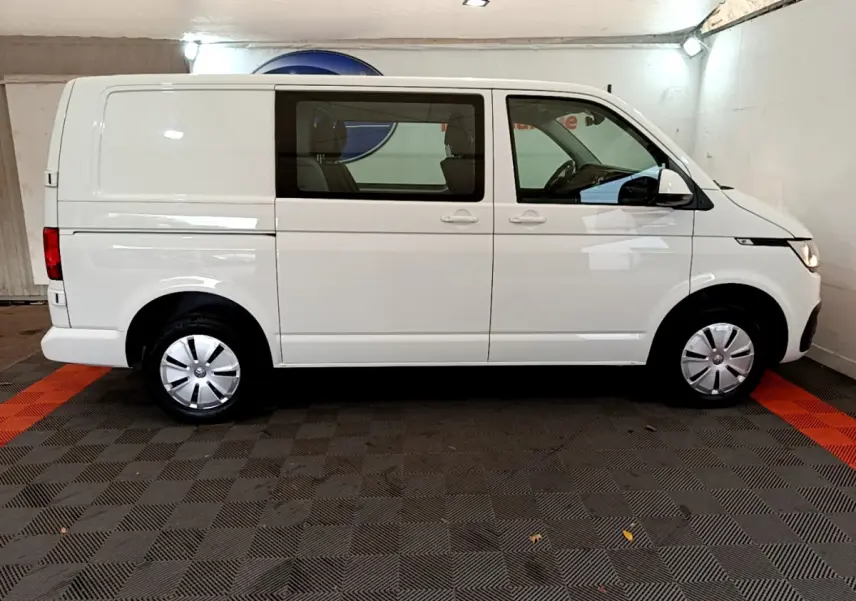 Vue latérale droite d'un Volkswagen Transporter blanc 2.0 TDi 150 DSG7 avec vitres avant teintées en intérieur.