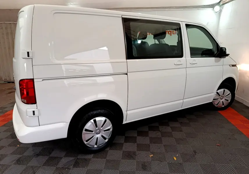 Vue latérale droite d'un Volkswagen Transporter blanc 2021 avec vitres avant teintées et jantes acier.