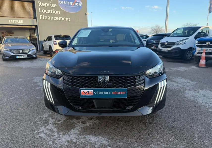 Peugeot 208 Hybrid 110 e-DCS6 Allure noire vue de face, avec feux diurnes LED en griffes distinctifs allumés.