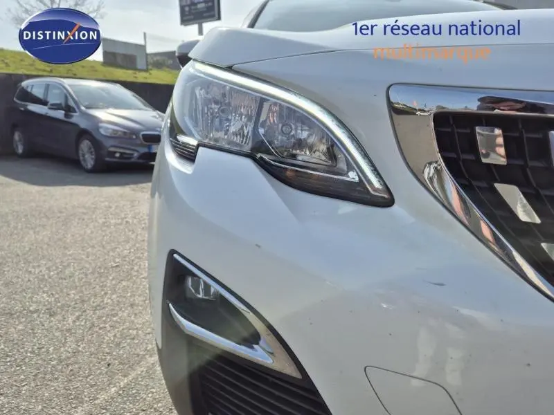 Gros plan sur le phare avant droit et la calandre chromée d'un Peugeot 3008 blanc nacré 2020.