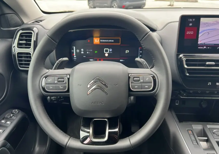 Vue intérieure centrée sur le volant cuir multifonctions d'une Citroën C5 Aircross Hybrid 2025 avec écran digital et console tactile.