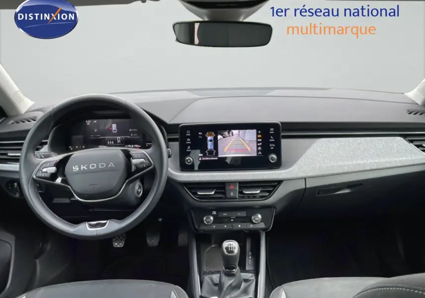 Vue intérieure frontale du tableau de bord gris noir de la Skoda Scala 2025 avec volant cuir et écran tactile central.