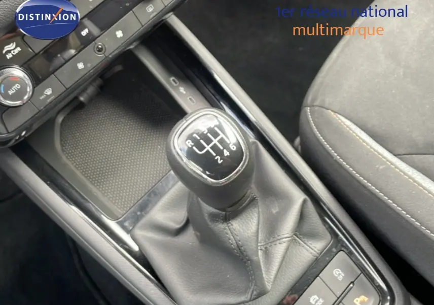 Gros plan sur la console centrale d’une Skoda Scala blanche, mettant en valeur le levier de vitesses manuel et la sellerie tissu gris noir.