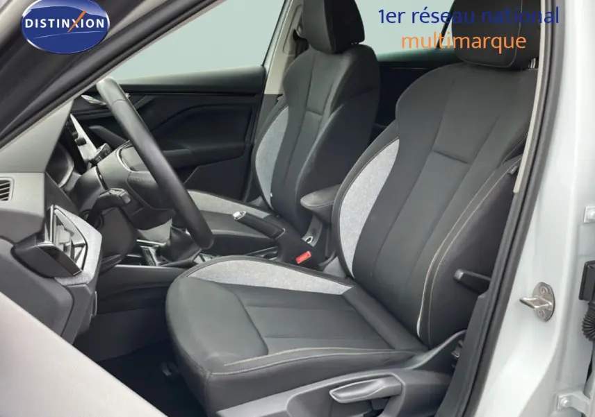 Vue intérieure côté conducteur de la Skoda Scala blanc glacier, sièges tissu gris noir avec volant multifonction.