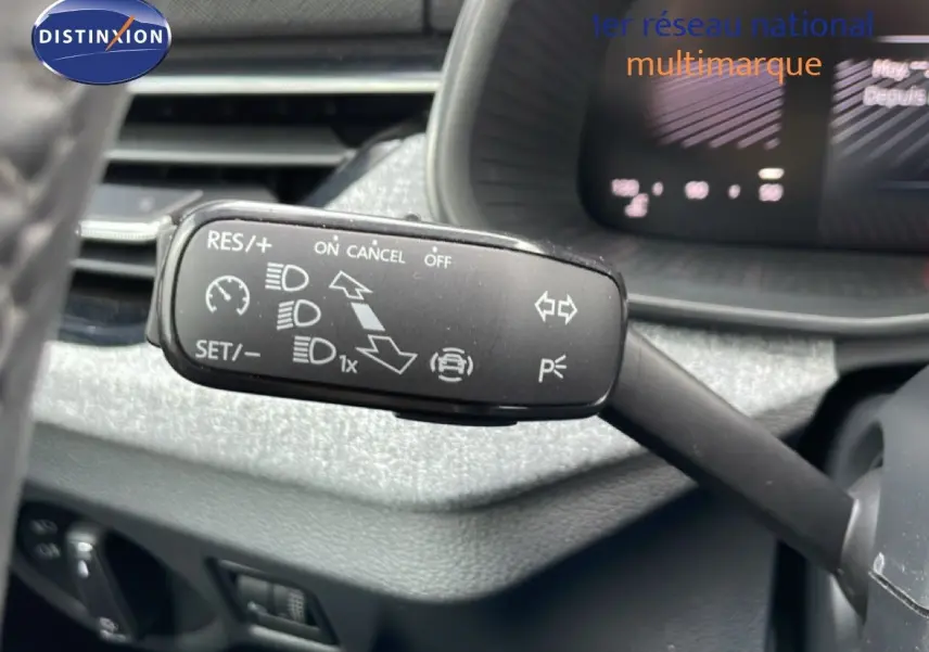 Gros plan sur la commande de régulateur de vitesse au volant d'une Skoda Scala blanc glacier, intérieur gris noir.