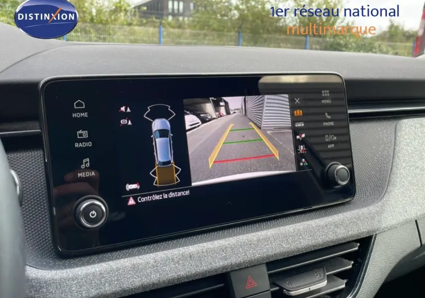 Écran tactile central affichant la caméra de recul avec vue arrière et alertes de distance dans un Skoda Scala blanc glacier.
