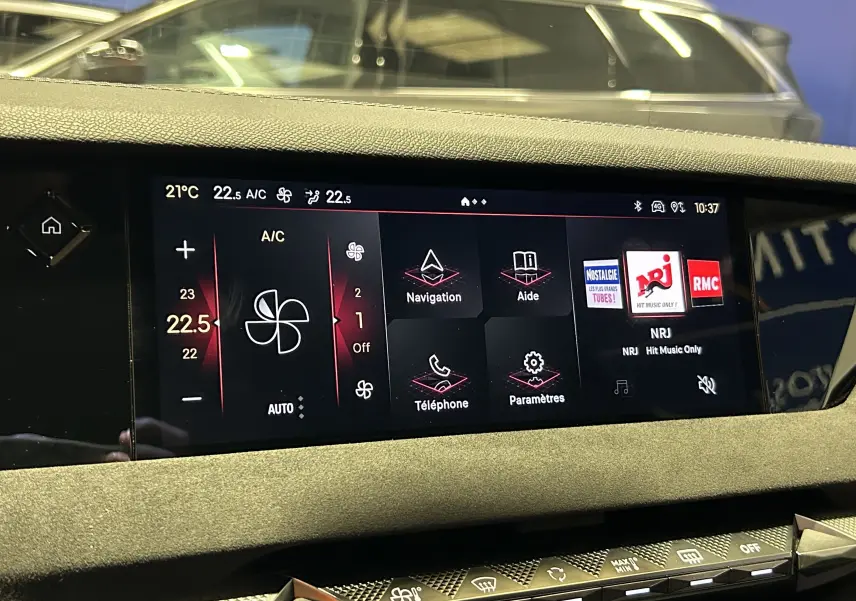 Écran tactile central du DS4 2024 affichant la climatisation, navigation et radio NRJ dans un intérieur noir.