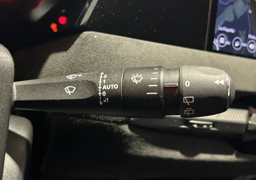 Gros plan sur la commande d'essuie-glace du DS4 2024 noir Perla Nera, avec affichage du tableau de bord en arrière-plan.