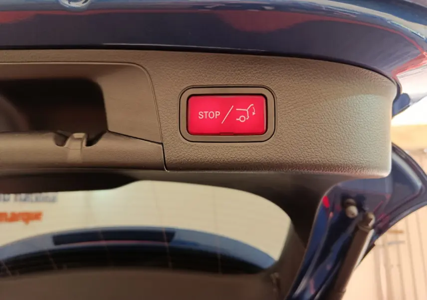 Bouton rouge stop pour fermeture électrique du coffre sur la partie intérieure du hayon d'un Mercedes GLA 250 e bleu 2024