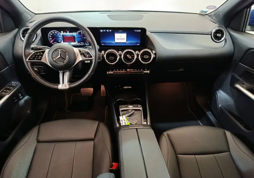Intérieur noir du Mercedes GLA 250 e 2024 vu de face, tableau de bord avec écran tactile et volant cuir multifonctions.