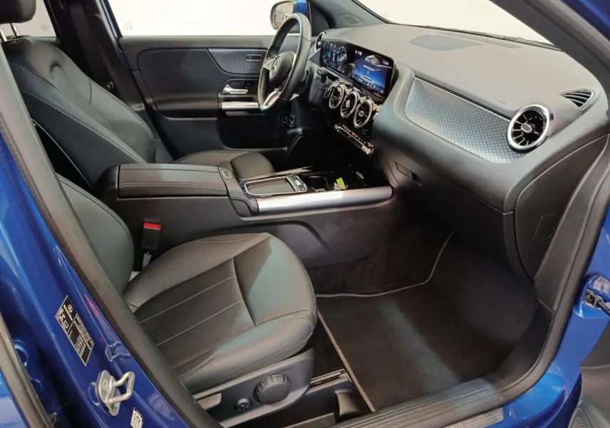 Intérieur côté conducteur du Mercedes GLA 250 e Business Line 2024 bleu, avec tableau de bord numérique et sièges cuir noirs.