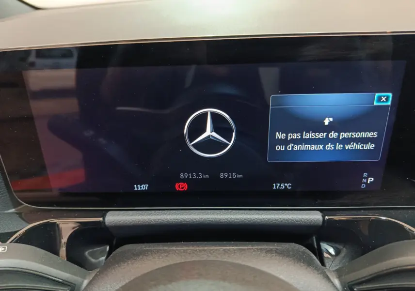 Affichage numérique du tableau de bord du Mercedes GLA 250 e bleu, avec logo central et message de sécurité.