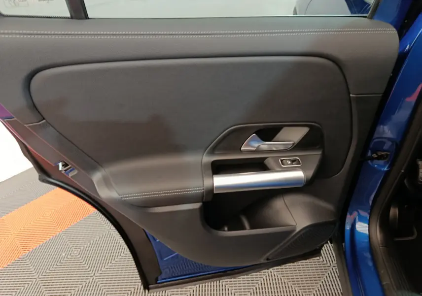 Gros plan sur la porte arrière gauche bleu d'une Mercedes GLA 250 e Business Line avec poignée argentée et bouton de verrouillage.