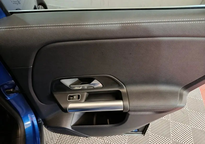 Gros plan sur la porte côté gauche bleu du Mercedes GLA 250 e Business Line avec poignée argentée et bouton de fenêtre.