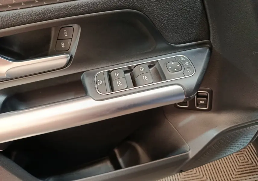Gros plan sur la commande des vitres et rétroviseurs côté conducteur du Mercedes GLA 250 e bleu 2024.