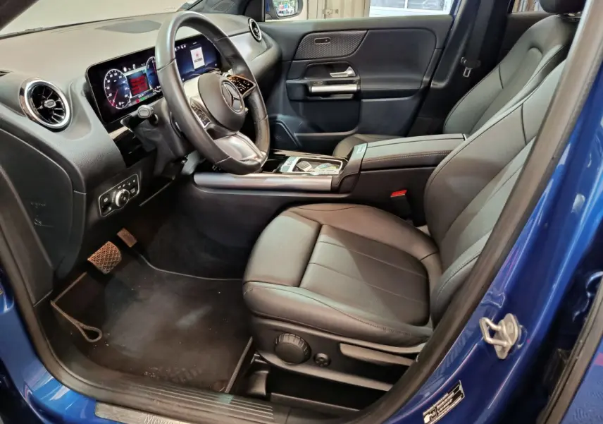 Intérieur côté conducteur du Mercedes GLA 250 e bleu 2024, volant cuir, tableau de bord digital et sièges noirs cuir.