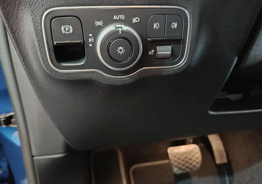 Gros plan sur les commandes d'éclairage et frein de stationnement du Mercedes GLA 250 e bleu, côté conducteur intérieur.