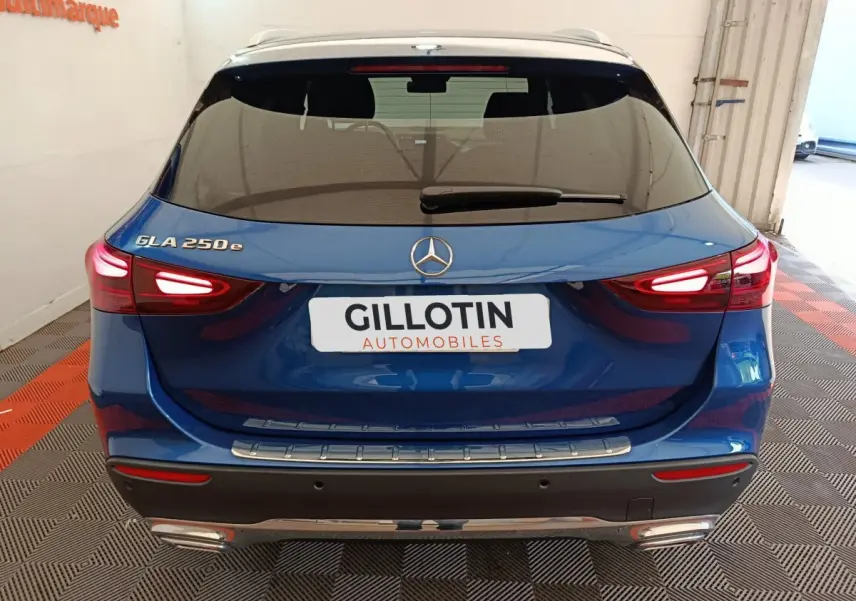 Vue arrière d'un Mercedes GLA 250 e bleu avec feux LED allumés et logo Mercedes visible sur le coffre.
