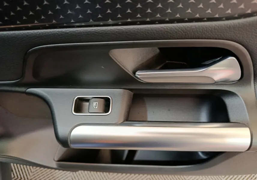 Poignée intérieure côté gauche avec bouton de verrouillage, finition noire et argentée du Mercedes GLA 250 e 2024.