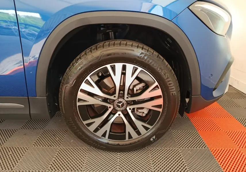 Gros plan sur la roue avant gauche du Mercedes GLA 250 e Business Line bleu avec jante alliage et logo Mercedes au centre.