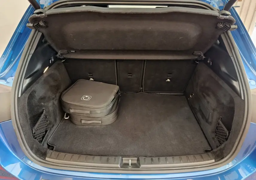 Coffre ouvert vu de l'arrière d'un Mercedes GLA 250 e Business Line bleu avec sac de rangement noir à l'intérieur.