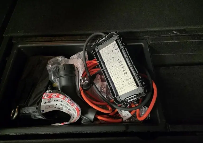 Chargeur électrique avec câble orange rangé dans le coffre du Citroën C5 Aircross Hybrid Rechargeable gris 2024