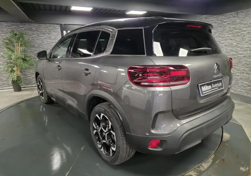 Vue 3/4 arrière droite d'un Citroën C5 Aircross Hybrid gris métallisé avec toit noir et jantes bi-ton 18 pouces.