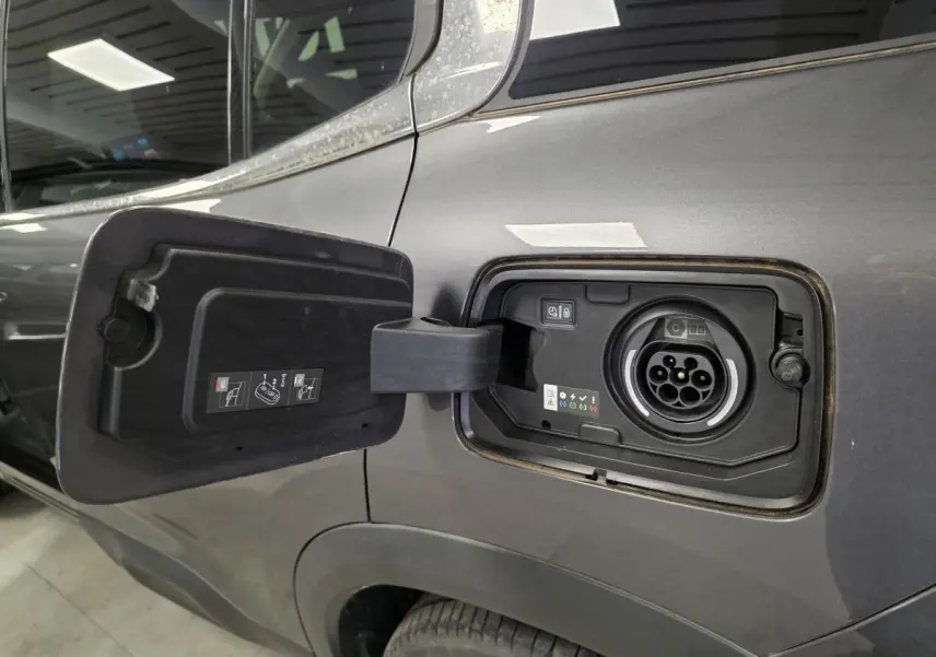 Prise de recharge hybride ouverte côté gauche d'un Citroën C5 Aircross gris métallisé 2024, détail du port de charge.