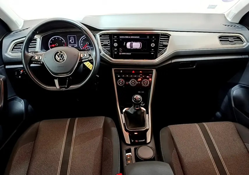 Vue intérieure frontale du tableau de bord et volant cuir noir du Volkswagen T-Roc 1.0 TSI avec boîte manuelle.