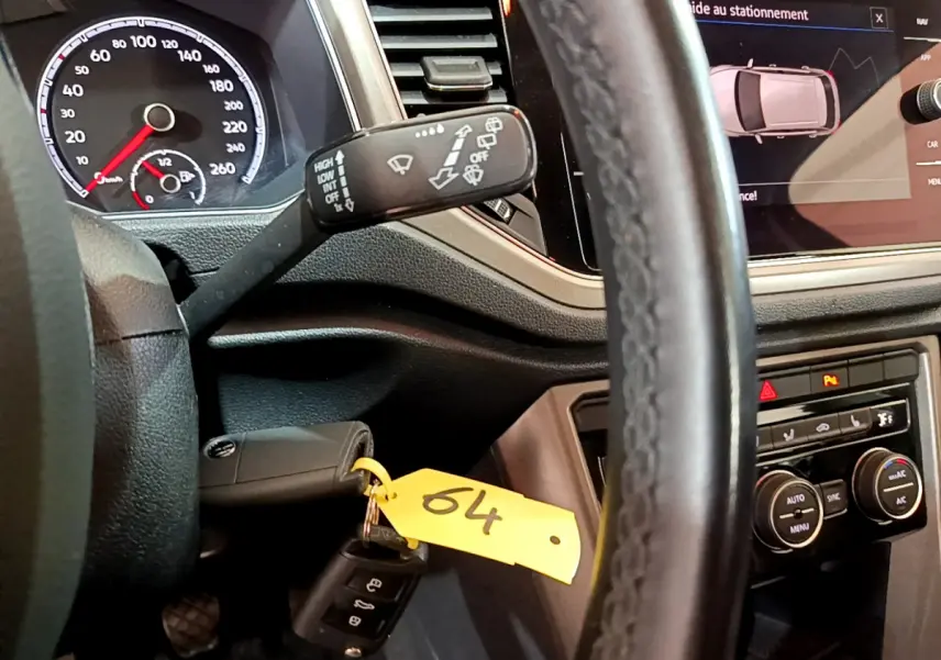 Vue intérieure rapprochée du volant cuir et du tableau de bord du Volkswagen T-Roc 1.0 TSI 110 Lounge avec écran tactile et commandes climatisation.