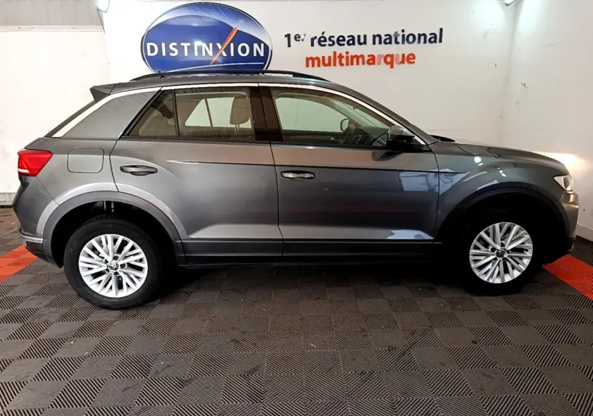 Vue latérale droite d'un Volkswagen T-Roc gris foncé 2021, avec jantes alliage et barres de toit noires.