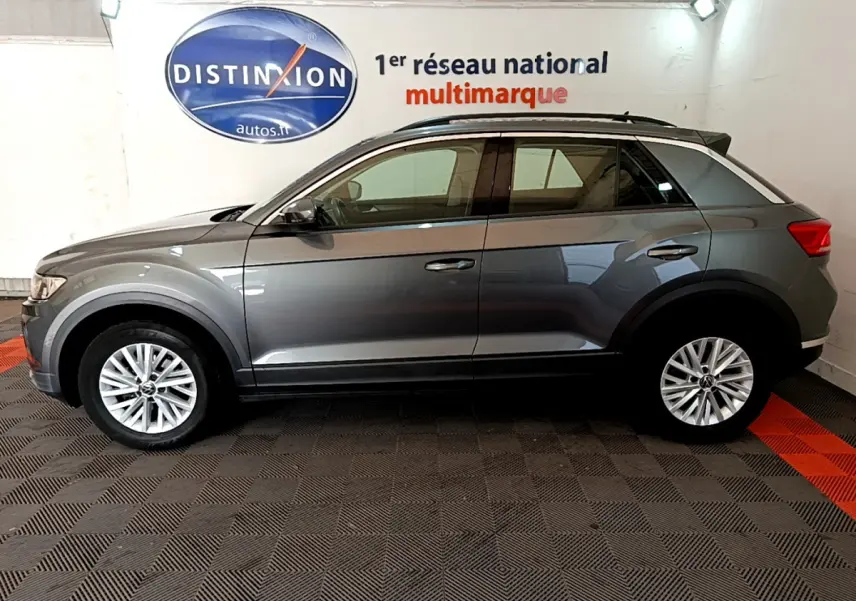 Profil droit d'un Volkswagen T-Roc gris foncé 2021, finition Lounge, avec jantes alliage et rails de toit noirs.