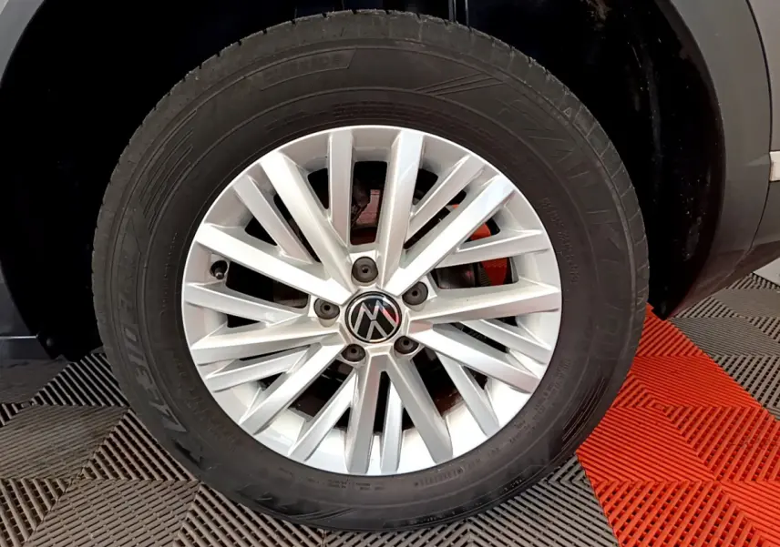 Gros plan sur la roue avant droite d’un Volkswagen T-Roc gris foncé, jante alliage argentée à multiples branches.