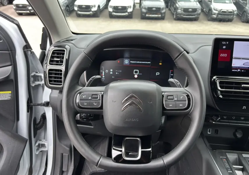 Vue intérieure centrée sur le volant cuir multifonctions du Citroën C5 Aircross Hybrid blanc, avec tableau de bord digital et écran tactile.