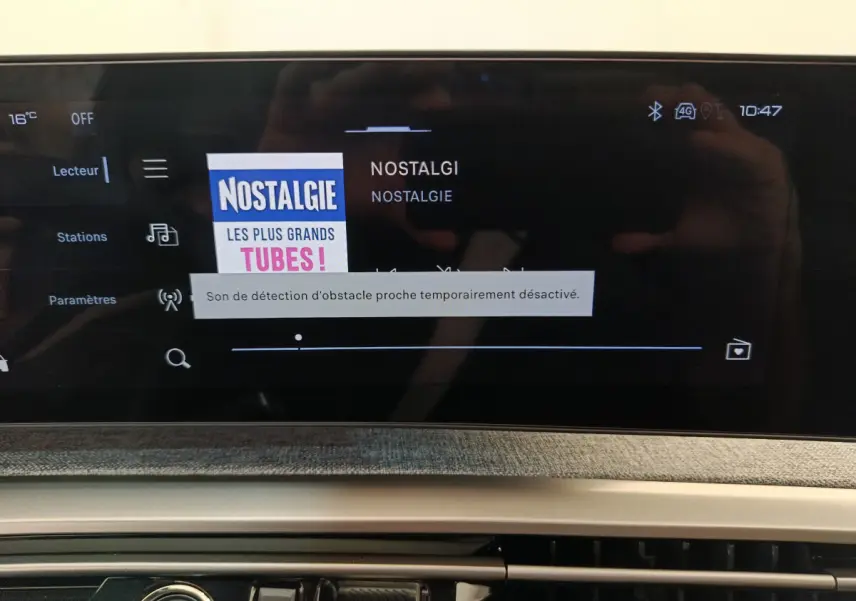 Écran tactile central affichant la radio Nostalgie dans l'habitacle du Peugeot 3008 noir, version hybride 2025.