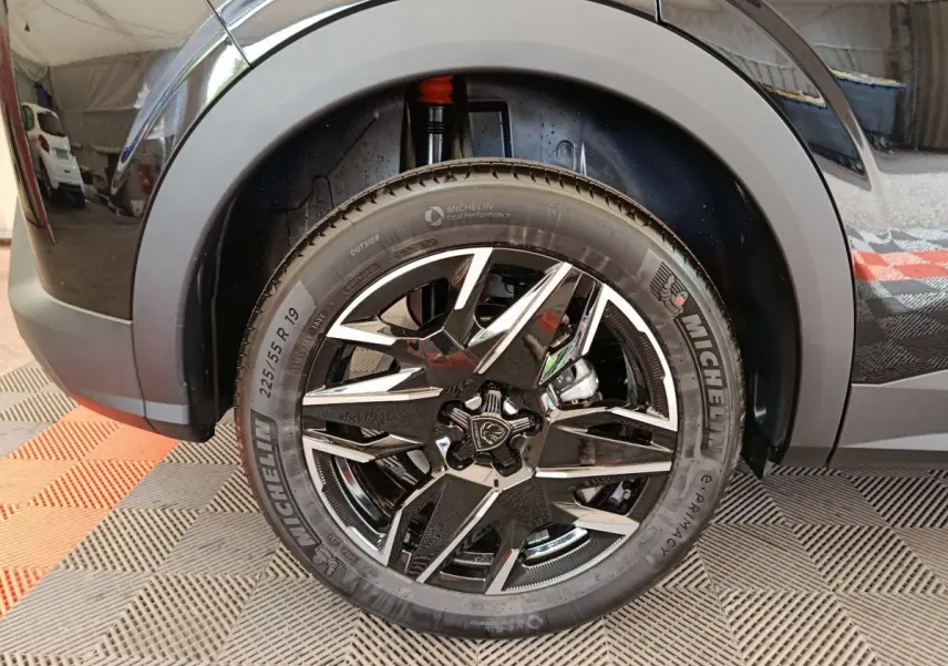 Gros plan sur la roue avant droite noire du Peugeot 3008 1.2 HYBRID 145 E-DCS6 GT avec jante alliage et pneu Michelin.