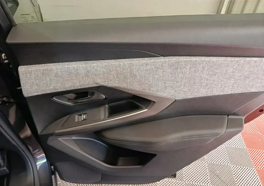 Gros plan sur la porte côté gauche du Peugeot 3008 noir, mettant en valeur le revêtement gris et les commandes intégrées.