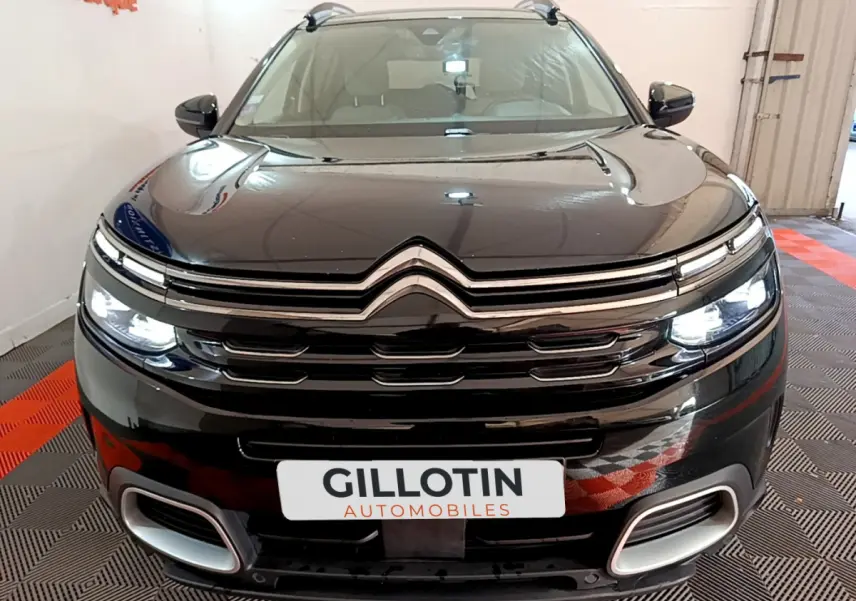 Vue frontale d'un Citroën C5 Aircross Hybrid noir avec feux LED allumés dans un showroom.