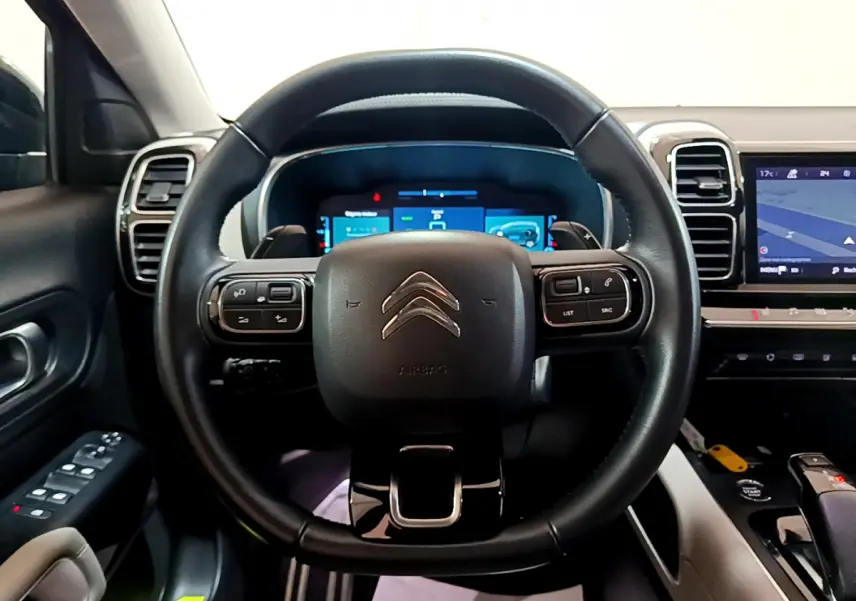 Vue intérieure centrée sur le volant cuir noir du Citroën C5 Aircross Hybrid avec tableau de bord digital et écran tactile.