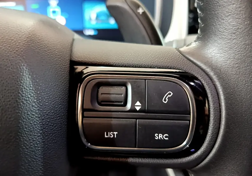 Gros plan sur les commandes gauche du volant cuir noir du Citroën C5 Aircross Hybrid 225 ë-EAT8 Shine, boutons multifonctions.