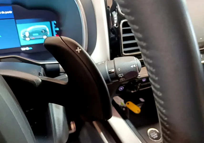Gros plan sur la palette de changement de vitesse droite et le volant cuir noir du tableau de bord du Citroën C5 Aircross Hybrid.