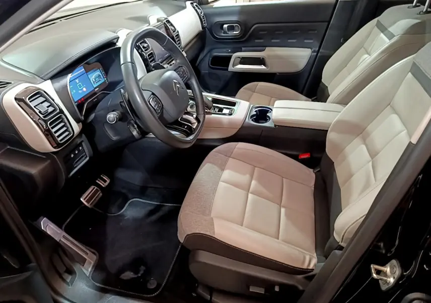 Vue intérieure côté conducteur du Citroën C5 Aircross Hybrid noir, sièges bicolores beige et gris, tableau de bord digital.