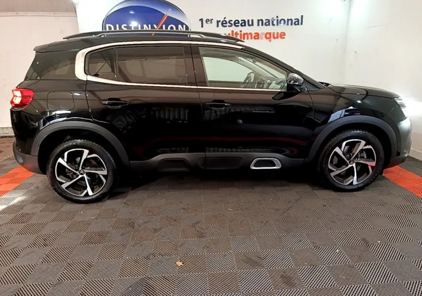 Vue latérale droite d'un Citroën C5 Aircross Hybrid noir 2021 avec jantes alliage et barres de toit chromées.