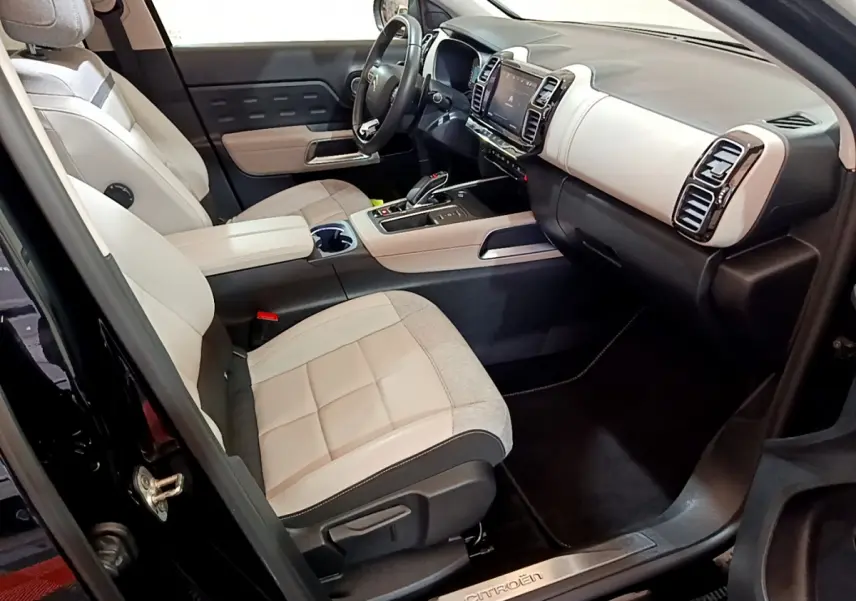 Intérieur avant du Citroën C5 Aircross Hybrid noir, sièges bicolores beige et gris, tableau de bord moderne avec écran tactile.