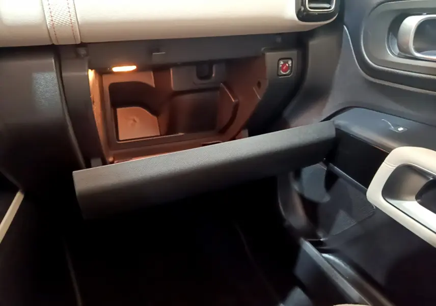 Vue intérieure côté passager du coffre à gants ouvert du Citroën C5 Aircross Hybrid 225 ë-EAT8 Shine, avec éclairage intérieur.