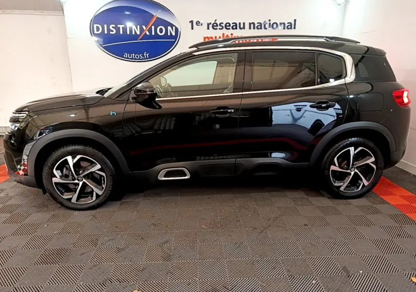 Profil côté gauche d'un Citroën C5 Aircross Hybrid noir 2021 avec jantes bicolores et barres de toit chromées.
