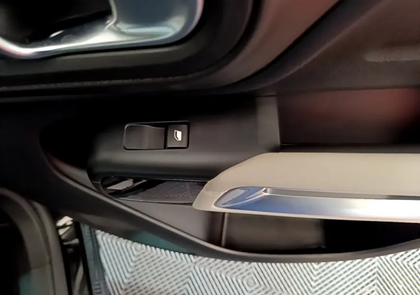 Détail de la commande de lève-vitre côté gauche sur la porte intérieure beige et noire du Citroën C5 Aircross Hybrid 225 ë-EAT8 Shine.