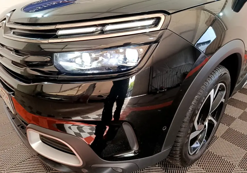 Gros plan sur l'avant droit noir du Citroën C5 Aircross Hybrid 225 ë-EAT8 avec phares LED allumés et jante stylisée.