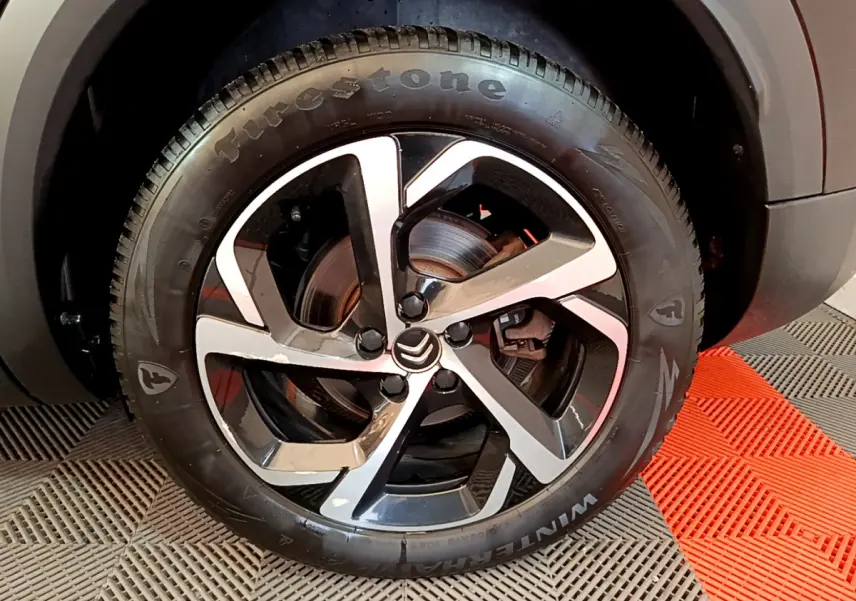 Gros plan sur la roue avant droite du Citroën C5 Aircross Hybrid 225 ë-EAT8 Shine noire avec jante alliage bicolore et pneu Firestone.